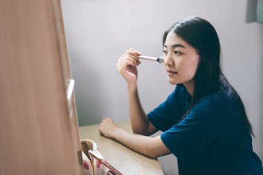 Portrait of single stills wellness lifestyle ready for day concept. Young adult asian woman makeup and face skincare before mirror in dress room at home. 