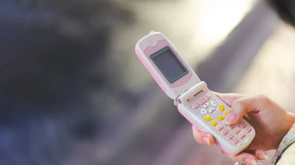 Y2Kのノスタルジアのトレンドファッションのためのピンクのフリップ電話を使用してティーンエイジャーの手 デジタルガジェットコンセプトによる2000年代の雰囲気 — ストック写真