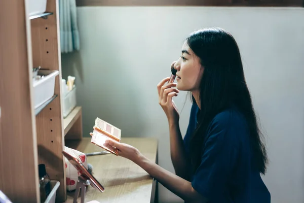 Portrait of single stills wellness lifestyle ready for day concept. Young adult asian woman makeup and face skincare before mirror in dress room at home.