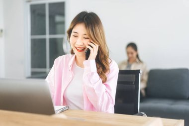 KOBİ 'nin ana ofis bağımsız kurma kavramını başlat. Masallar ve müşteri hizmetleri için telefon kullanan Asyalı genç bir iş kadını.