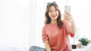 People lifestyle with technology concept. Young adult single asian woman using digital mobile phone for social message dating or shopping online in bedroom.