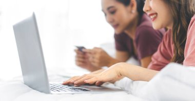 Yakın plan kadın, dizüstü bilgisayarını klavyeye basıyor. İnsanlar interneti modern yaşam tarzları için kullanıyorlar. Beyaz battaniyeli arka plan