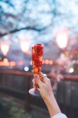 Japan Tokyo city Nakameguro sakura matsuri festival famous destination. Vertical closeup strawberry sparkling wine popular menu. Night background with bokeh.  clipart