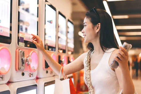 People city lifestyles with buying shopping consumerism. Young adult asian woman play gashapon at game center. Happy smile face at indoors department store.