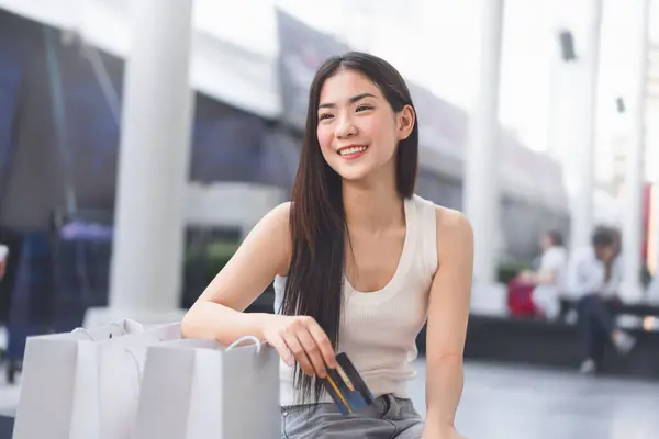People city lifestyles with buying consumerism. Portrait young beautiful face asian woman holding credit card and shopping bags. Happy smile spending money on vacations