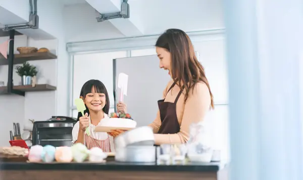 Mutlu Asyalı anne ve kızı mutfakta yemek pişiriyor. Akşam yemeği için hazır yemek. Ev yapımı tarif. Evde ebeveyni olan bir çocuk ile birlikte boş yaşam tarzları.