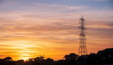 Yüksek voltajlı elektrik hatlarının silueti gün doğumunda ya da günbatımında renkli bir gökyüzüne karşı. Yüksek kalite fotoğraf
