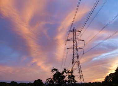 Güzel bulutlu bir gökyüzünün arka planında yeşil bir alandan geçen yüksek voltajlı elektrik hatları. Yüksek kalite fotoğraf