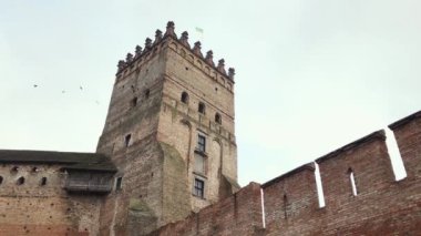 Kuşlar Kale Kulesi 'nin etrafında dönüyorlar. Orta Çağ Kalesi. Brick Asterle. 14. yüzyılda kurulmuş olan Kale. Ukrayna Bayrağı.