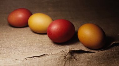 Painted Easter Eggs on a Brown Linen Bedspread. Red, Brown and Yellow Chicken Eggs.