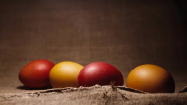 Easter celebrations. red, brown and yellow chicken eggs. Painted easter eggs on a brown linen bedspread.