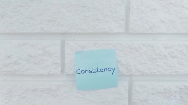 Concept of consistency. Consistency written in letters hanging on the white wall.