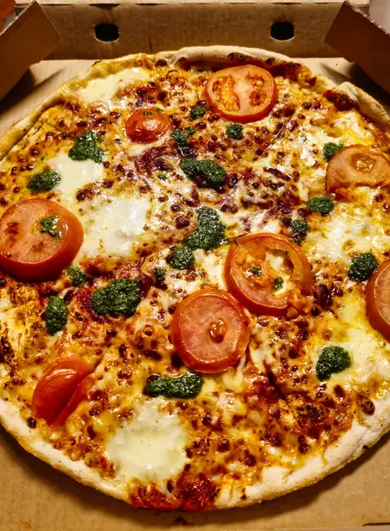 Pizza Caprese in the pizza box - tomato sauce, mozzarella, spinat, tomate, pizza beans, pesto, mini mozzarella balls. High quality photo