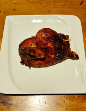 Izgara tavuk, yarım güzel ve kızarmış bir tabak ve ahşap masa. Yüksek kalite fotoğraf