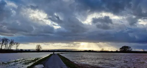Kolenfeld wunstorf dirt road flooding with great cloudy sky and sunbeams germany. High quality photo