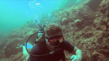 Bir adam, deniz biyolojisinden etkilenen bir dalış ustasının rehberliğinde, bir dalış ekipmanıyla mercan resifinin yakınındaki okyanusu keşfediyor.