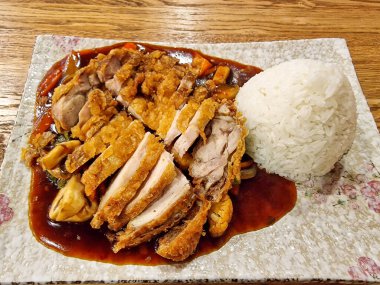 Lezzetli bir tabak kızarmış balık ve tavuk eti. Köy ahşap bir masada beyaz pirinçle servis ediliyor. Lezzetli deniz ürünleri ve kümes hayvanları yemek tarifi sunuluyor.