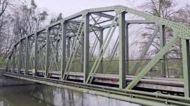 Çelik ve kompozit malzemeden yapılmış bir köprü, arka planda ağaçlar ve Maschsee Hanover yakınlarındaki elektrik hatları ile Leine Nehri üzerinde uzanır.