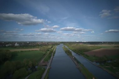 Nefes kesen bir hava manzarası, güneşli bir günde Mittelland Kanalı 'nda güzel mavi bir gökyüzü ve tüylü bulutlar altında salınan sakin bir nehri yakalar.