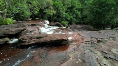 Ağaçlar ve kayalarla çevrili kayalıkların üzerinde güzel bir şelale, gür bir ormanın ortasında, doğanın harikalarını ve akışkan manzaraları sergiliyor Phu Quoc Vietnam Khu du lich sinh thai