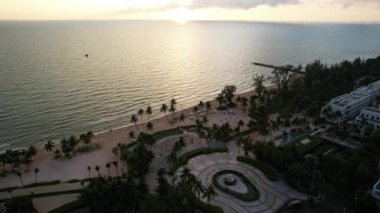 Uçsuz bucaksız bir su kütlesine tepeden bakan palmiye ağaçlı bir sahil manzarası sakin kentsel tasarım elementleri Phu Quoc Adası Long Beach Vietnam ile çarpıcı bir doğal manzara yaratıyor.