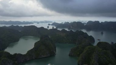 Halong Körfezi Hanoi Vietnam Asya manzarası ufuk çizgisinde tüylü kümülüs bulutları ile berrak bir gökyüzü altında dağlarla çevrili büyük bir su kütlesi ile pitoresk bir doğal manzara.