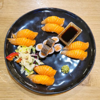 Ahşap bir masada sergilenen lezzetli sosla kaplı siyah deniz ürünleri suşisi tabağı. Bulaşık takımı ve sofra takımı Hanover Almanya 'nın bu leziz mutfağının sunumunu artırıyor.