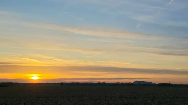 A hazy image of a red sky at morning with the sun rising over a field. The afterglow illuminates the horizon in a beautiful natural landscape Wunstorf