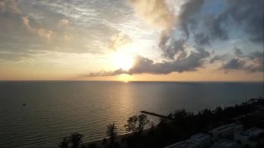 Güneş ufukta batarken suyun üzerine altın bir parıltı saçıyor gökyüzünde renkli bulutlarla güzel bir doğal manzara yaratıyor Phu Quoc Adası Long Beach Vietnam