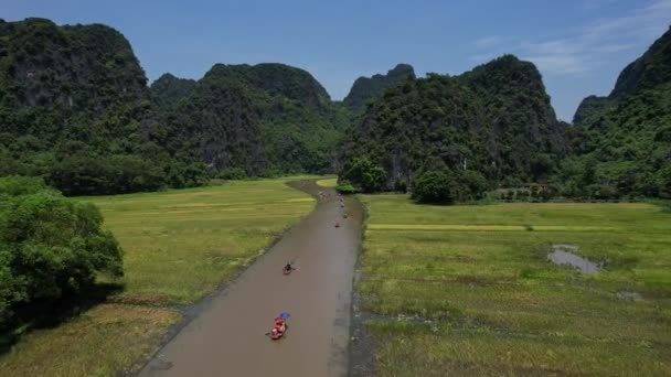 開かれた空の下に 山々を背景に川を下ってカヤックしている人々のグループ 自然の風景は木 斜面に囲まれています ニンビンベトナム アジア ドローンビュー — ストック動画