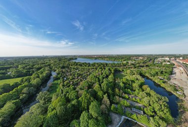 Ağaçlar, bitkiler ve arka planda bulutlu bir gökyüzünün altında akan bir nehrin hava perspektifi Hanover Ricklinger Teiche Almanya