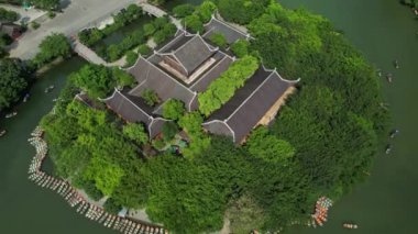 Ağaçlarla çevrili bir bina gölün ortasındaki küçük bir adada yer almakta ve çarpıcı bir doğal manzara yaratmaktadır. Nin-Binh Trang An Pagoda Vietnam Asya insansız hava aracı görüntüsü.