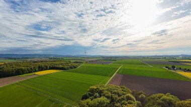 Yeşillik çayırlar, ağaçlar ve arka planda tüylü kümülüs bulutları olan açık mavi gökyüzü ile doğal bir manzara - Hanover Seelze Almanya FPV Drone görüşü