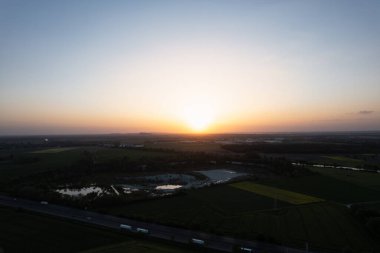Günbatımının büyüleyici bir hava görüntüsü canlı yeşil bir manzaranın üzerine yansıyor. Arkaplanda açık bir gökyüzü ve ufuk görünüyor. İnsansız hava aracı, Hanover Kolenfeld Almanya 'yı görüyor. 