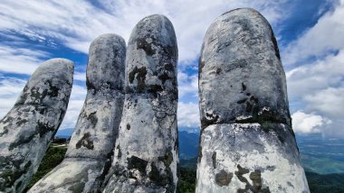 Kayalardan yapılmış görkemli bir el heykeli, Vietnam Da Nang Ba Na Hills Asya 'nın nefes kesici doğal manzarasıyla çevrili bir dağın zirvesinde gururla durur.