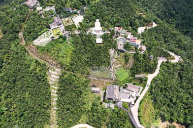 Bir tepenin tepesinde yer alan ve doğal bir manzarada yemyeşil ağaçlarla çevrili bir köyün havadan görüntüsü. Vietnam Da Nang Ba Na Tepeleri Asya 'nın ortasında binalar ve yollar var.
