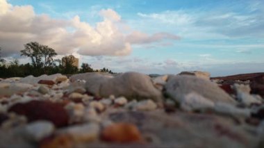 Kumlu kumsalda, açık mavi gökyüzünün altında dağınık kümülüs bulutları olan bir kaya yığını duruyor. Ufuk sakin suyla buluşur, sakin doğal bir manzara yaratır Phu Quoc Adası Long Beach