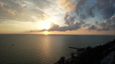 Uçsuz bucaksız okyanus üzerinde nefes kesici bir hava manzarası, renkli bulutlar ve alacakaranlıkta sudan yansıyan alacakaranlık Phu Quoc Adası Long Beach Vietnam 'da canlı bir günbatımını yakalar.