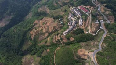 Dağlarla çevrili güzel bir köyün hava manzarası. Resmedilmeye değer manzarayı kesen sakin bir yol. Doğa ve seyahat için ideal içerik Ha Giang döngüsü Vietnam Asya 5K