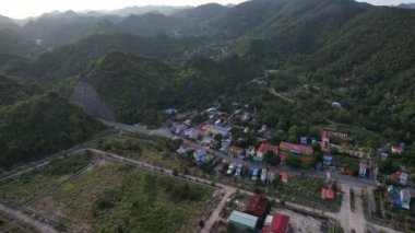 Cat Ba Adası 'nın kuş bakışı manzarası muhteşem dağların arasına yuva yapmış binalar, evler, bitkiler ve ağaçlarla kaplı bulutlu gökyüzü altında doğal manzarayı noktalayan 4k manzara Halong Körfezi Hanoi