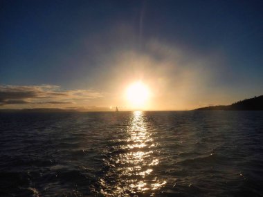 Güneş yavaşça ufkun altına batıyor. Whitsunday Adası, Queensland, Avustralya yakınlarındaki su kütlesinin el değmemiş yüzeyine güzel yansımalar yansıtıyor.