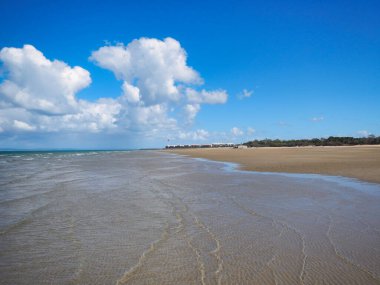 Hervey Bay Fraser Avustralya 'nın üzerinde zarif bir şekilde yüzen yumuşak, tüylü beyaz bulutlarla süslenmiş berrak, parlak mavi bir gökyüzü içeren güzel bir sahil manzarası.