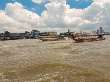 Sarmal bir nehrin muhteşem manzarası, Bangkok Tayland 'ın canlı arka planına karşı geleneksel teknelerle süslenmiş.