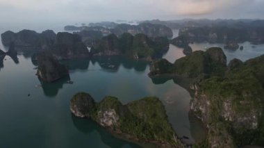 Geniş bir göl, yükselen dağların arasına yerleşmiş. Sıvı yüzeyindeki gökyüzünü ve bulutları yansıtarak büyüleyici bir doğal manzara yaratmış. Halong Körfezi Hanoi Vietnam.