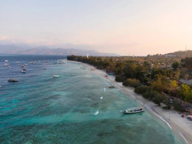 Geniş bir hava manzarası, Bali gili Adaları 'nın yakınlarındaki trawangan adalarında zarif bir şekilde yüzen birkaç teknenin bulunduğu pitoresk bir plajı gösteriyor.