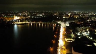 Parlayan ışıklar ve gökyüzünü aydınlatan neşeli havai fişeklerle parıldayan şehir siluetinin çarpıcı bir gece görüntüsü. Hannover Maschsee Hiperlapse 2025