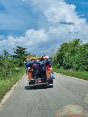 İnsanlar, parlak mavi gökyüzü Zanzibar 'ın altında çeşitli mallarla dolu büyük bir kamyonda birlikte seyahat ediyorlar.
