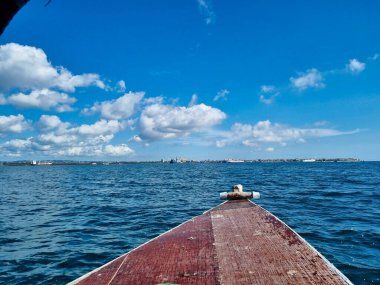 Sakin suları yakalayan sakin ve huzurlu bir tekne manzarası tüylü bulutlarla bezenmiş parlak mavi bir gökyüzünü yansıtıyor Zanzibar Afrika