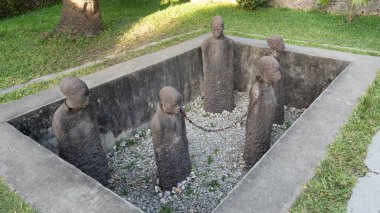 Çimenlik yeşili Afrika Zanzibar ile çevrili batık bir alana yerleştirilmiş beş etkileyici taş heykelin büyüleyici görüntüsü.