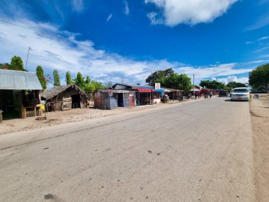 Huzurlu ve huzurlu bir yol kenarı manzarası, canlı, mavi gökyüzü Zanzibar Afrika 'nın altına kurulmuş yerel dükkanların güzelliğiyle sergileniyor.